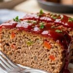 Classic homemade meatloaf with a glossy ketchup glaze sliced on a plate
