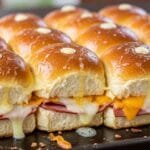 Baked ham and cheese sliders on Hawaiian rolls with melted cheese and buttery glaze