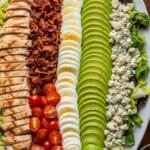 Homemade Cobb salad with chicken, bacon, eggs, avocado, tomatoes, and blue cheese arranged on a platter