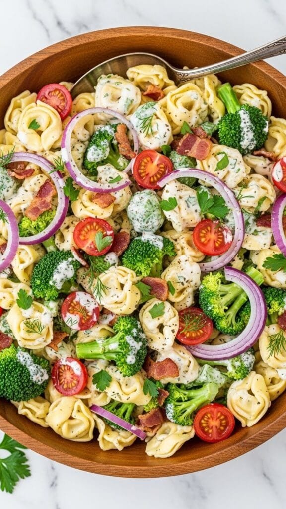 Creamy tortellini pasta salad with bacon, cheddar cheese, red onion, and ranch dressing served cold