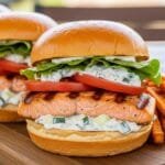Fresh salmon burgers served on buns with lettuce and creamy tzatziki dressing