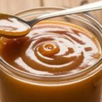 smooth homemade caramel sauce in jar with golden texture