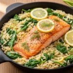 One skillet salmon with lemon orzo and spinach cooked together in a pan