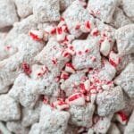 White chocolate peppermint puppy chow coated in powdered sugar with crushed candy canes
