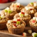 Apple Cinnamon Baked Oatmeal Cups (Healthy, Meal-Prep Friendly & Naturally Sweetened) Apple cinnamon baked oatmeal cups with golden tops and fresh apple pieces arranged on tray