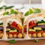 High-protein Mediterranean chickpea wraps filled with roasted vegetables, whipped feta, and tahini sauce