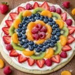 Rainbow-style fruit pizza with cream cheese frosting and fresh fruit.