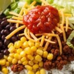 Easy Taco Rice Bowl One-pot taco rice bowl made with seasoned ground beef, white rice, black beans, corn, shredded lettuce, cheddar cheese, and salsa served in a dinner bowl