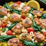 One-pot Greek lemon chicken and rice with spinach, chickpeas, tomatoes, and feta in a skillet