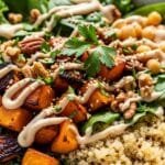 Maple-roasted butternut squash quinoa bowl with greens, chickpeas, nuts, and creamy tahini dressing