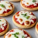 Quick & Easy English Muffin Pizzas (15-Minute Recipe) Crispy English muffin pizzas topped with melted mozzarella and tomato sauce on a baking sheet
