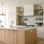 Modern kitchen with a functional island, smart pantry storage, textured backsplash, open shelving, and stylish lighting.