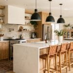 Rustic modern kitchen with natural wood cabinets, white island, black pendant lights, and warm neutral decor